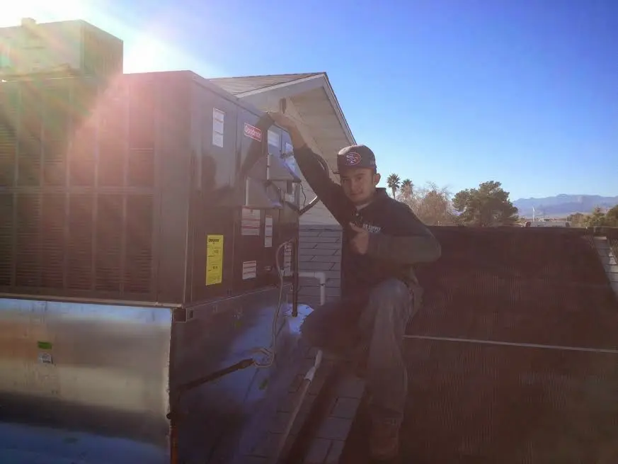 HVAC technician performing Heat Pump Repair on a rooftop unit in Edwards